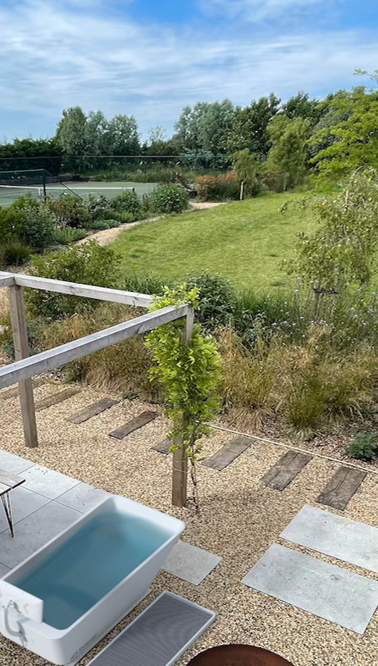 A whiteout cold plunge from Primal Plunges in a lush backyard near a tennis court